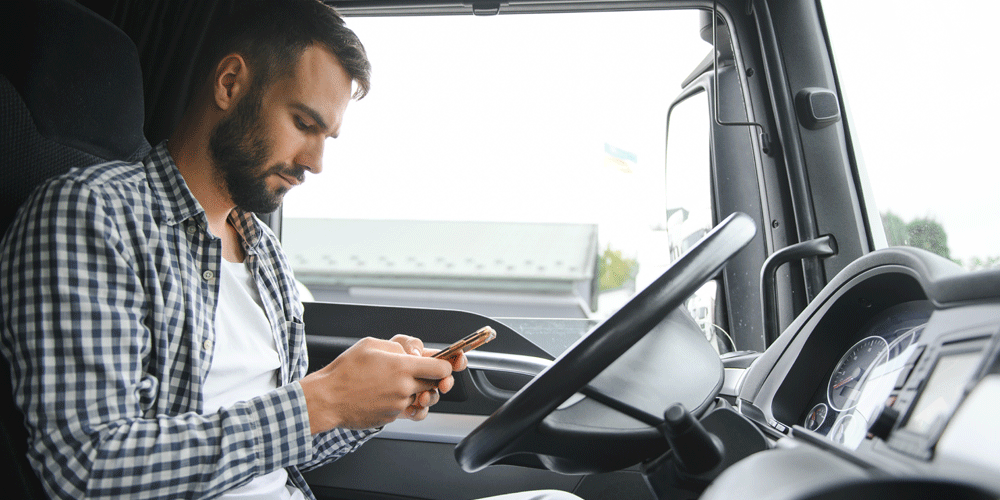 Truck driver sitting in the driver's seat of his cab on the phone.